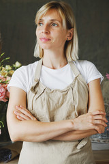 woman in apron standing on flower background. Entrepreneurship, florist, craftsman, artisan, craft, service, cook, barista, small business, workplace concept