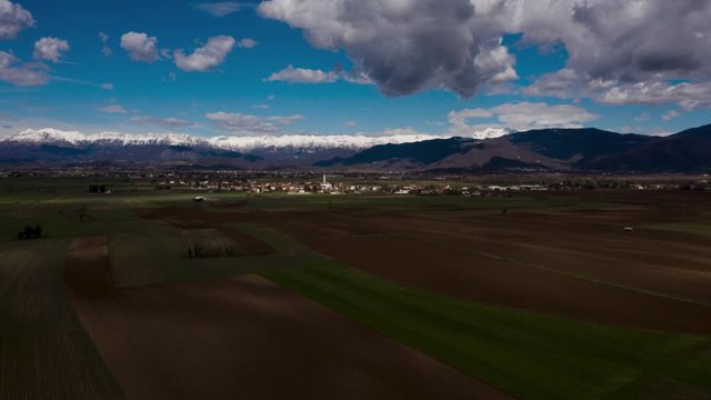Aerial Hyper lapse of beautiful Alps mountains country side fields. Clouds shadows moving on ground. Drone wide angle view. Friuli Venezia Giulia, Italian landscape.