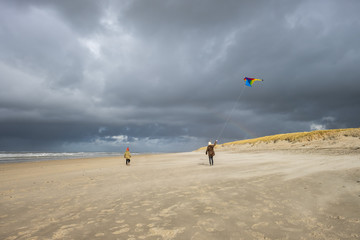 Young girl and boy with a colorful kite on a deserted winter beach