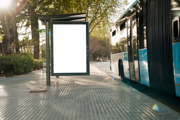 White blank vertical billboard at the bus stop on the city street. In the background of buses and roads. Sketch. Poster on the street next to the road.
