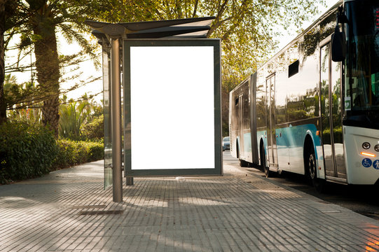 White Blank Vertical Billboard At The Bus Stop On The City Street. In The Background Of Buses And Roads. Sketch. Poster On The Street Next To The Road.