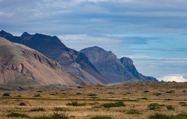 Icelandic landscape with mountains, blue sky and green grass on the foreground. West fjord part