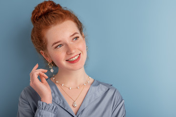 Young happy smiling fashionable  redhead woman wearing trendy pearl necklace, earrings, ring. Close...