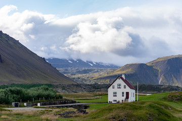 Fototapeta na wymiar Farmhouse on hill in Iceland with cloudy sky and nice view on background 