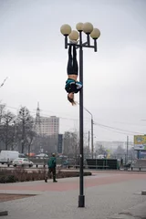 Foto op Aluminium Young attractive Girl hanging by feet upside down on the street light in the street. super extreem. concept of courage and meditation © Hladchenko Viktor