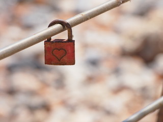 A red metal lock with a heart inscription