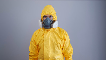 A man in a chemical protection suit on a gray background.