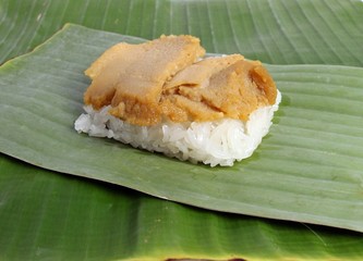 Thai dessert, steamed sticky rice, custard wrapped in banana leaves.