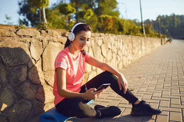 A sports girl in headphones is resting listening to music after training.