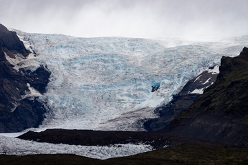 Glacier with ash in the ice with melted water and Icelandic landscape 
