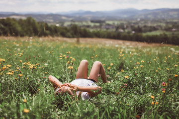 Attractive girl relaxing on the green grass on the top of the mountains in the morning