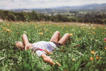 Attractive girl relaxing on the green grass on the top of the mountains in the morning