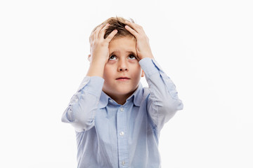 A school-aged boy in a blue shirt holds his head in his hands. Fatigue and apathy. Isolated on a white background.