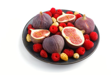 Fresh figs, strawberries and raspberries on blue ceramic plate isolated on white background. side view