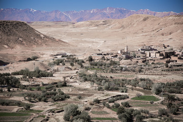 Oasis near the ancient village hidden under the hills and mountains on background