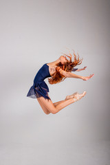 Young, beautiful, red-haired girl performs a jump ballet