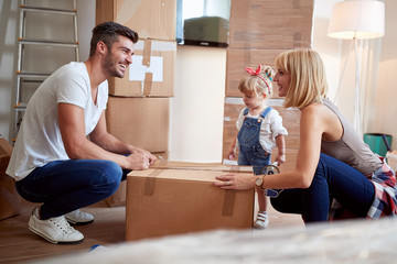 young parents unpacking boxes  in new apartment. new apartment, new beginning,  concept