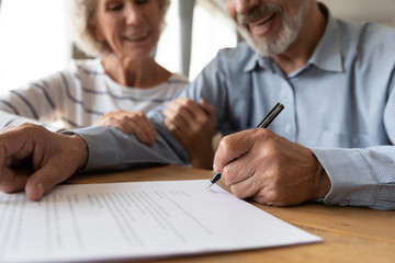 Close up of 60s husband and wife sit at desk sign health insurance contract close deal, smiling old mature couple spouses put signature on document make good agreement, elderly healthcare concept - obrazy, fototapety, plakaty