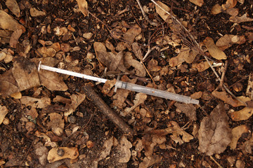thin syringe addict lies on the ground in dry foliage, addiction concept