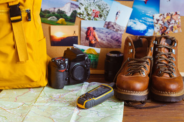 Travel accessories on the rustic wooden background near inspirational printed photos
