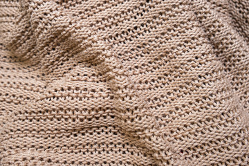 Crumpled folded beige, brown knitted fabric background, woolen knitwear plaid close up