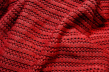 Crumpled folded dark red knitted fabric background, woolen knitwear plaid close up
