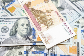 One hundred rubles lying on american dollars as a symbol of weakness russian national currency rub and strengthening of american dollar usd
