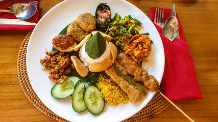 Traditional Indonesian meal consisting of different varieties of local food. Mixture of vegetables, grilled meat and steamed rice. Balanced diet. Trying new dishes.