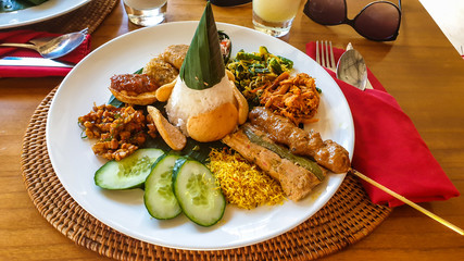 Traditional Indonesian meal consisting of different varieties of local food. Mixture of vegetables, grilled meat and steamed rice. Balanced diet. Trying new dishes.