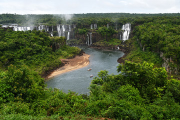 Iguazu roaring waterfalls against a jungle and gray sky