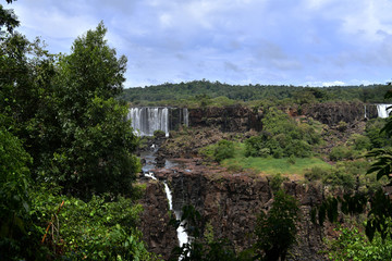 Naklejka premium Iguazu roaring waterfalls against a jungle and gray sky