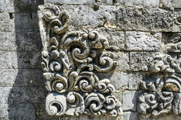 A close up on ornaments in the Uluwatu Temple, Bali, Indonesia, craved in stone wall. Traditional and historical site. Very detailed and time taking decoration. Masterpiece