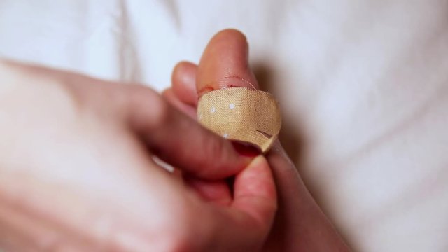 Abrasion on the foot . Nurse applying antiseptic band-aid plaster on the injured leg in blood with a red wound. Medical treatment.