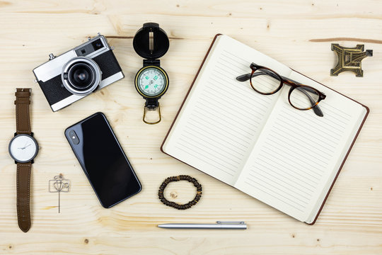 Composition with travel items, notebook, compass, camera, smart phone, watch.