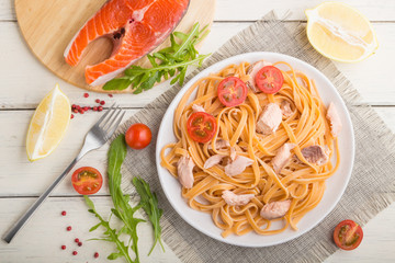 Semolina pasta with salmon and salmon steak on a white wooden background. Top view, close up.