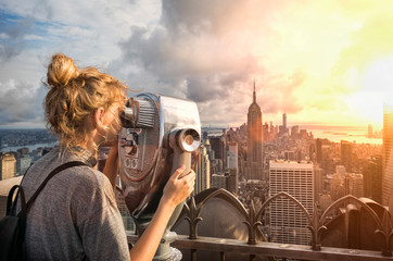 Young girl looking out over New York city at sunset