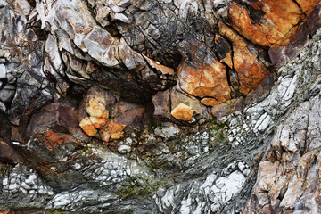 The texture of the rocks of the cliff with mixed stones in color.