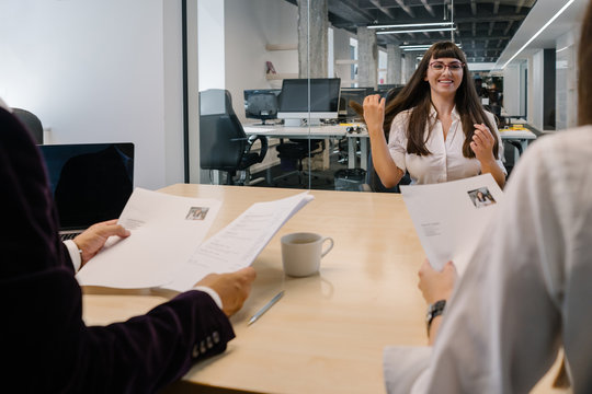 Cheerful job applicant at job interview begining conversation with company recruiters looking at her work resume