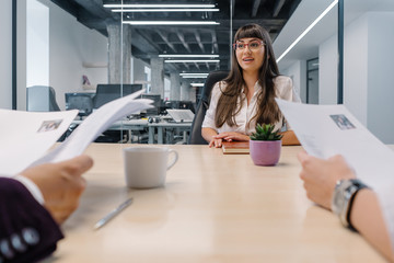 Talented young woman assuring recruiters with her strong arguments at a job interview