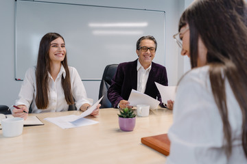 Two recruiters candidly smiling and welcoming a new hire at a job interview