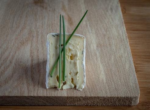 Slice of cheese with green onion on cutting  wooden board, high resolution photo