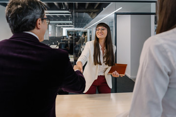 Young woman job applicant charming recruiters at a job interview with a candid smile and a friendly handshake