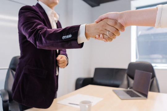Human resources manager greeting new job applicant with a firm handshake at the begining of the candidate selection process