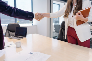Friendly handshake between recruiter and new woman intern at the end of successful candidate...