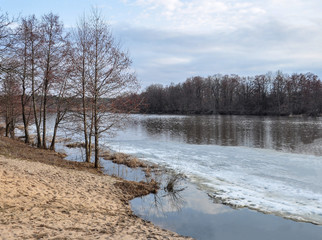 Spring landscape with the river opening from the ice.Melting snow.Trees grow along the banks