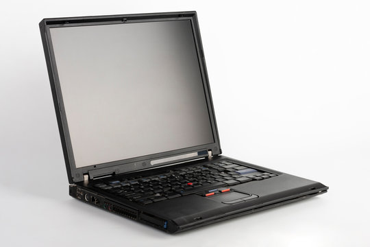 Old laptop on white background, which was produced in 2005, outer cover reinforced titanium, metal hinges, red trackpoint