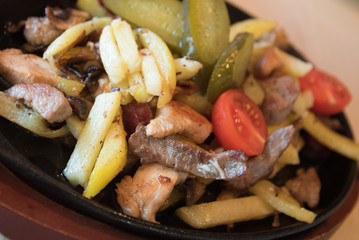 Fried potatoes with chicken and vegetables. The dish is served directly on the pan.