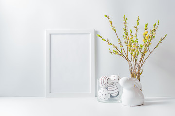Home interior with easter decor. Mockup with a white frame and willow branches in a vase on a light background