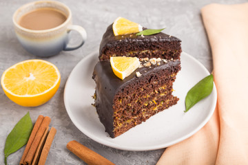 Homemade chocolate cake with orange and cinnamon with cup of coffee on a gray concrete background. side view, selective focus.