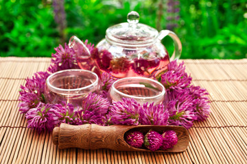 Obraz na płótnie Canvas Clover flower tea in the glass cups and teapot on a bamboo table.